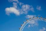 Ferris wheel with a partially cloudy blue sky background